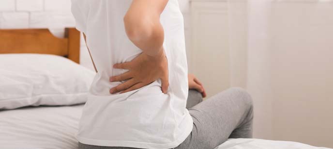 Person with hand on lower back experiencing back pain.